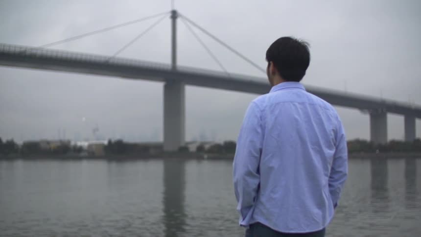 Man stands by the water on a cloudy day