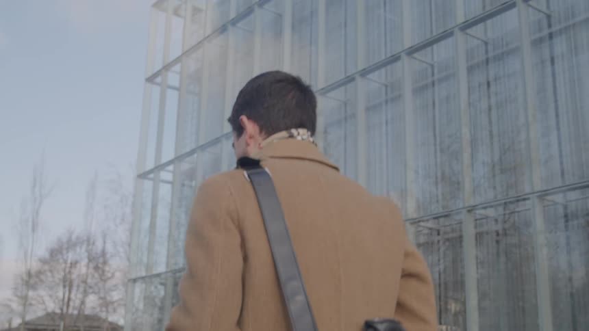 A man walking his bike by a building