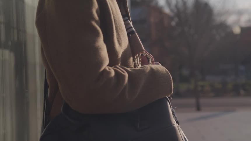 Person outdoors with a black leather bag