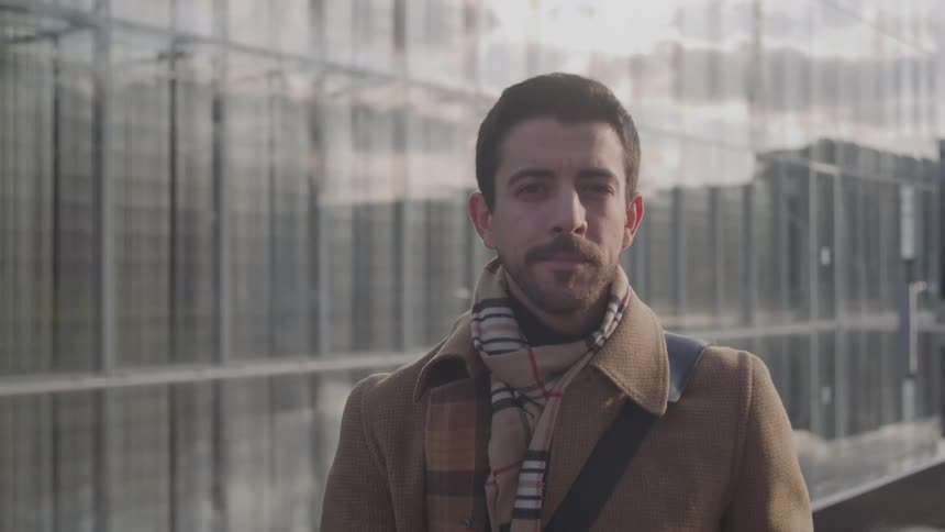 The man stands in front of the reflective building