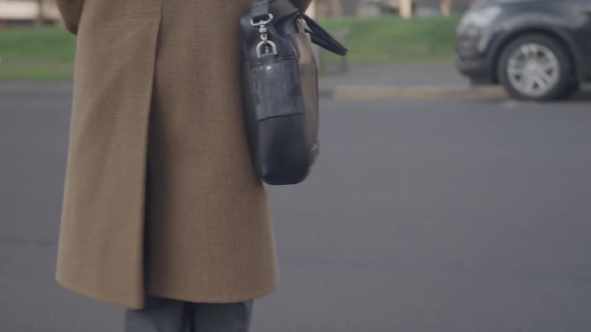 A person walks down a street with a bag over their shoulder