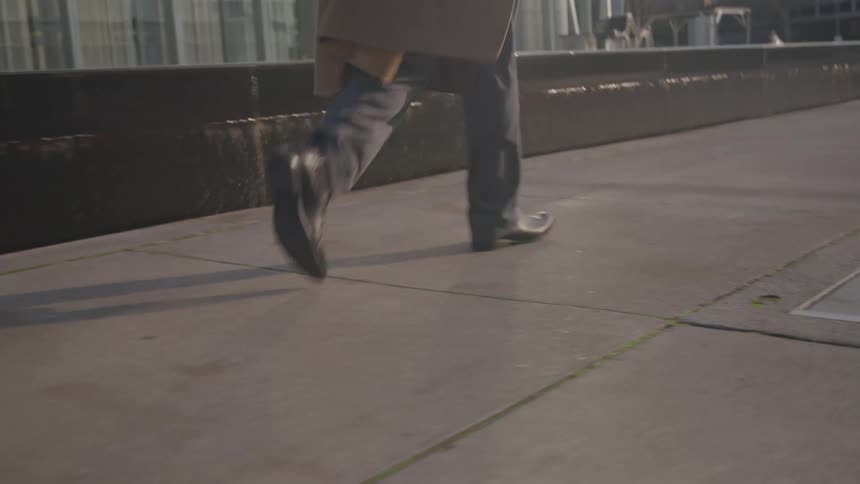 The man walks on the sidewalk during the day
