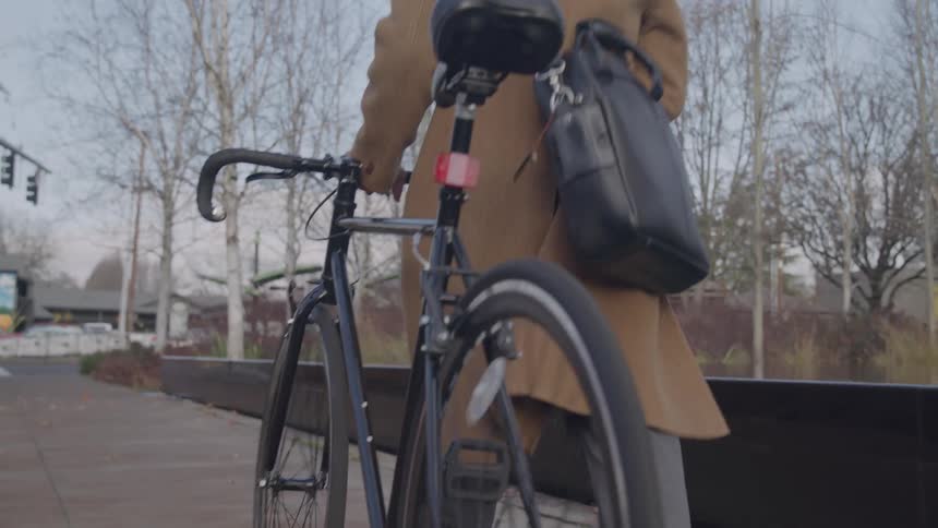 The man is pushing his bicycle on the sidewalk