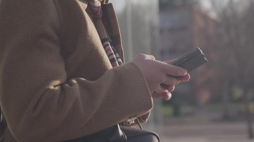 Close up of a young man using a mobile phone while standing outdoors in a city during daytime