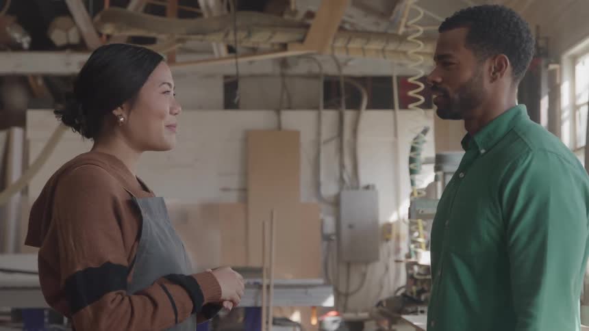 Woman in apron talking to a man in an indoor space