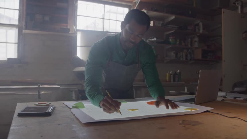 The man is writing on the workbench