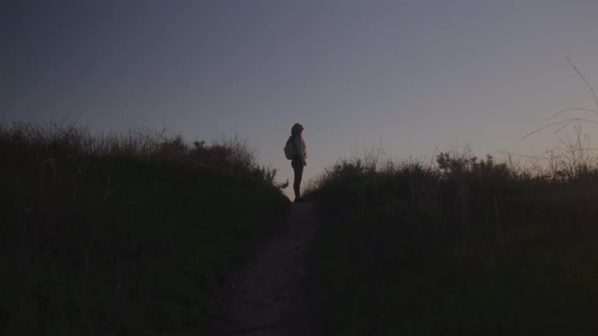 The woman looks up at the sky on the trail