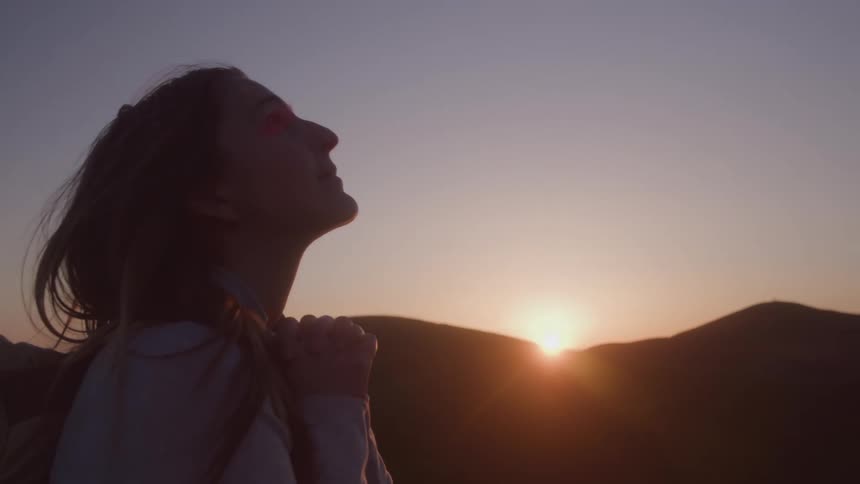 The woman looks up by the mountains as the sun rises