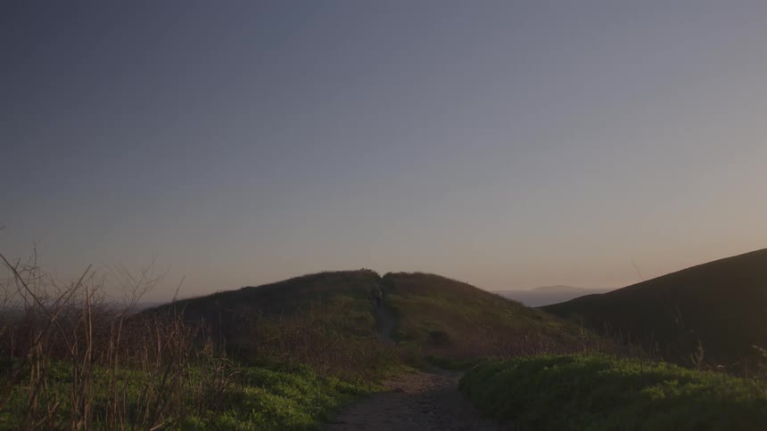 A path up a grassy knoll at dusk
