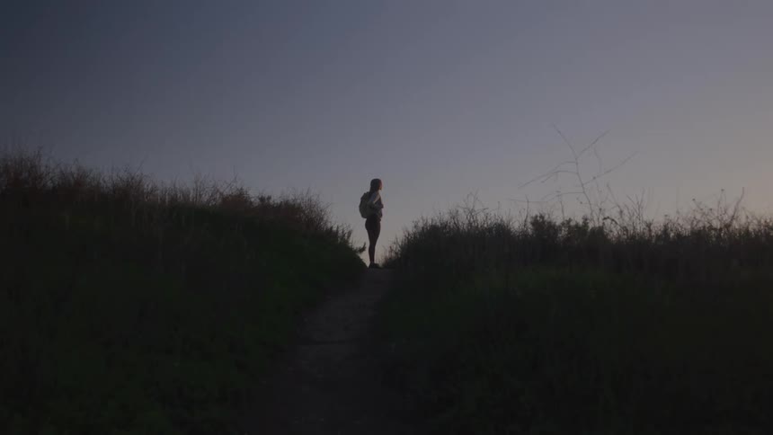 A young woman stands on a path between two patches of grass