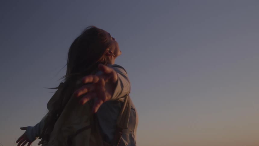 A woman standing outside arms outstretched