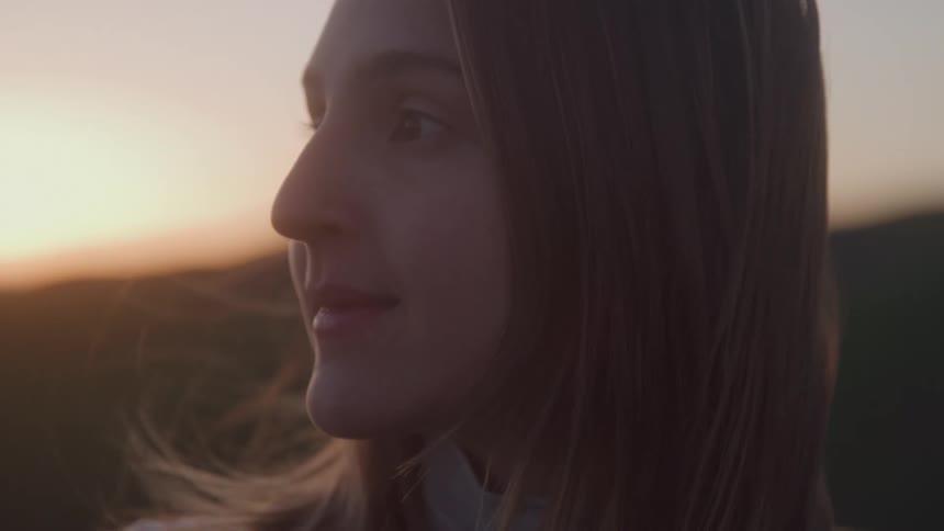 As the sun rises the womans hair blows in the wind