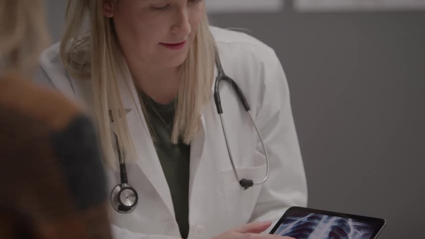The doctor shows her patient an x ray on the tablet