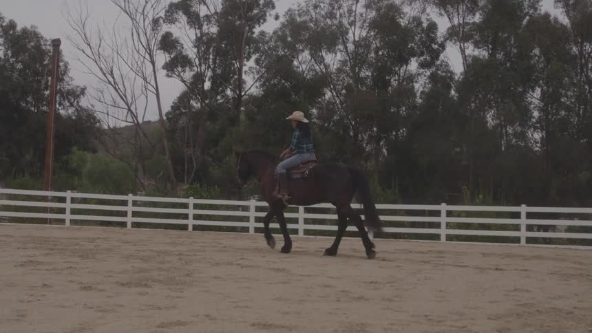 Woman riding a horse in a coral on a ranch