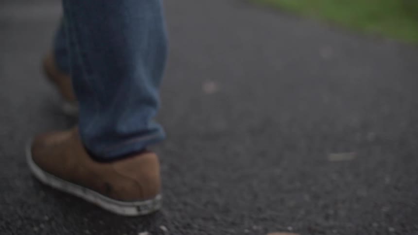 A tight shot of someone's feet as they walk down a road