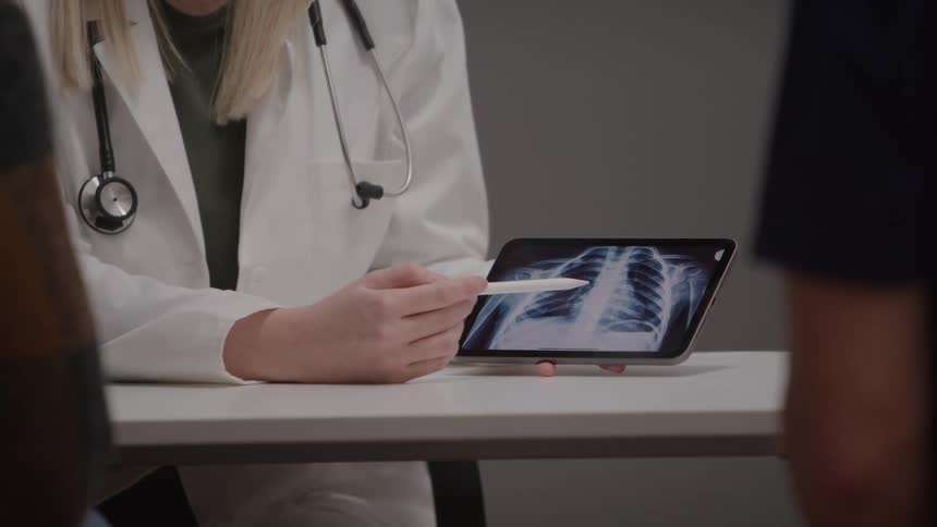 Doctor holds a pen and shows a chest xray on a tablet to a patient