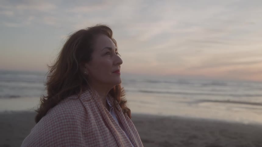 The woman looks up at the sky on the beach