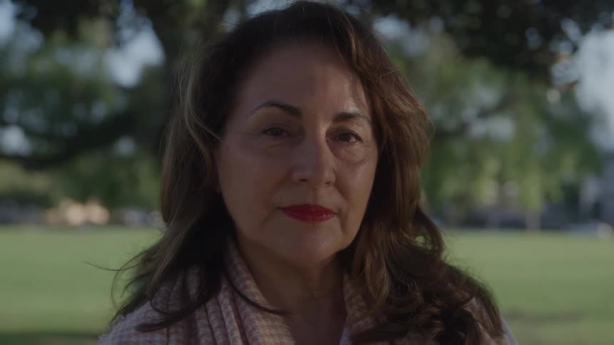 A woman stands outdoors and looks at the camera
