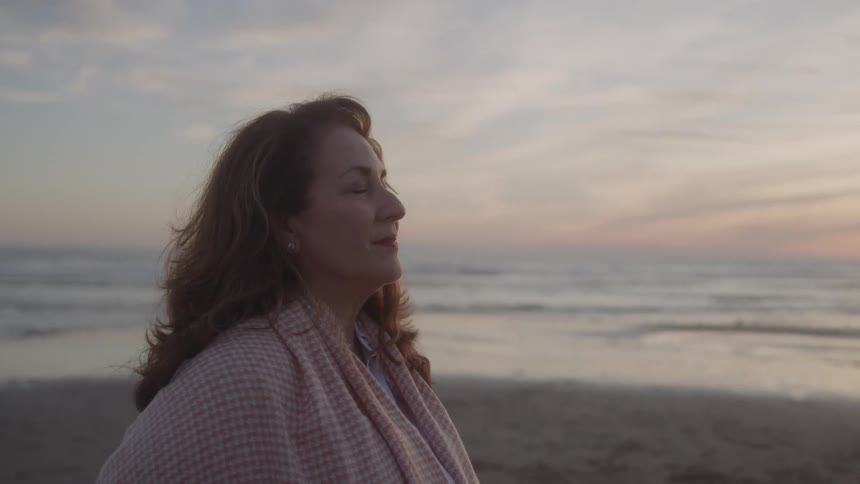 Brownhaired woman enjoys the sunset by the sea