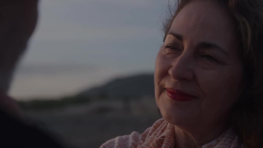 Woman smiles with a loving expression while looking at someone in front of her