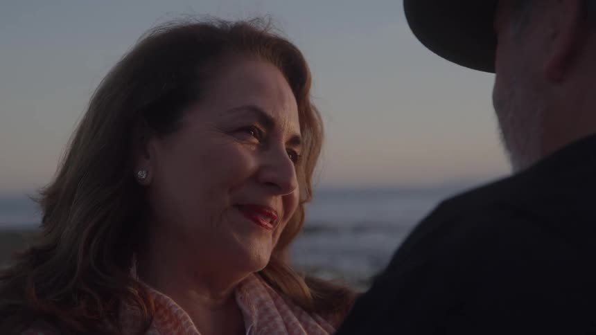 The man and woman smile at each other outside