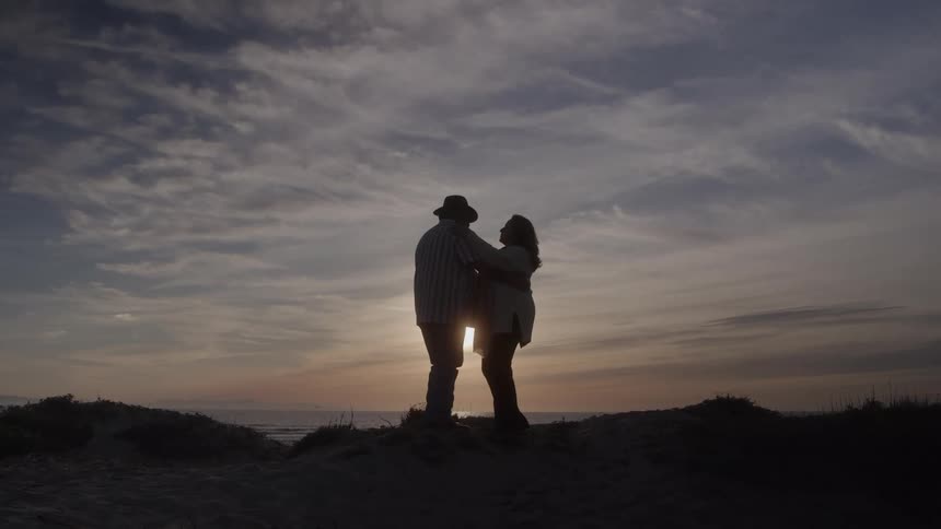 The man and woman hug as the sun rises
