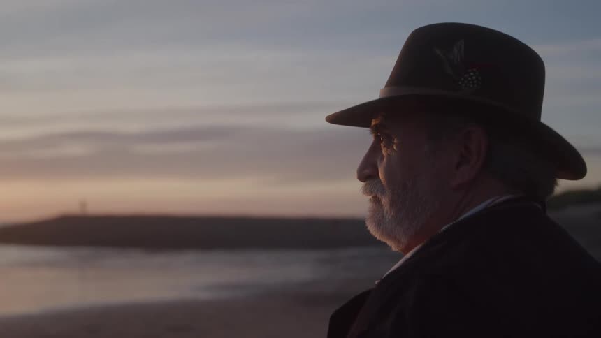 Man with a hat watching the sunset by the sea