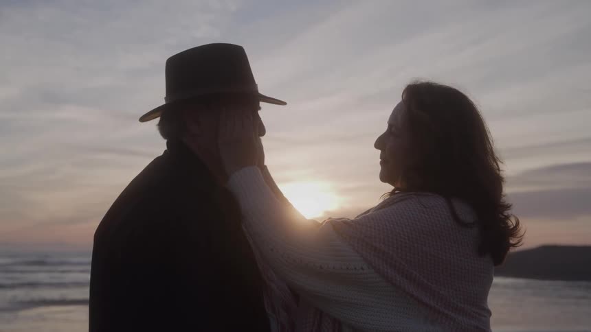 The woman touches the man at sunrise