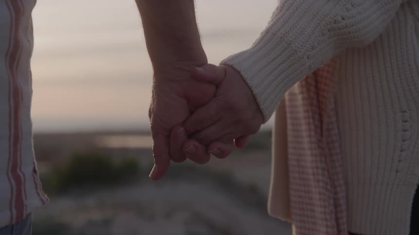 Intertwined hands of a couple outdoors
