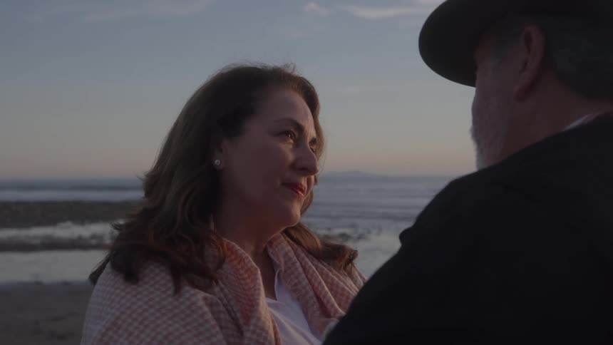 Woman smiling while looking at the man in front of the sea