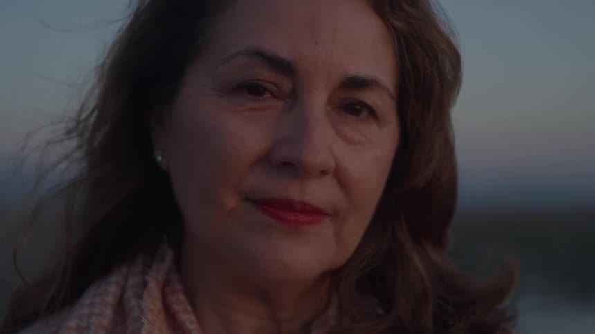 A womans face is shown outdoors as she looks at the camera