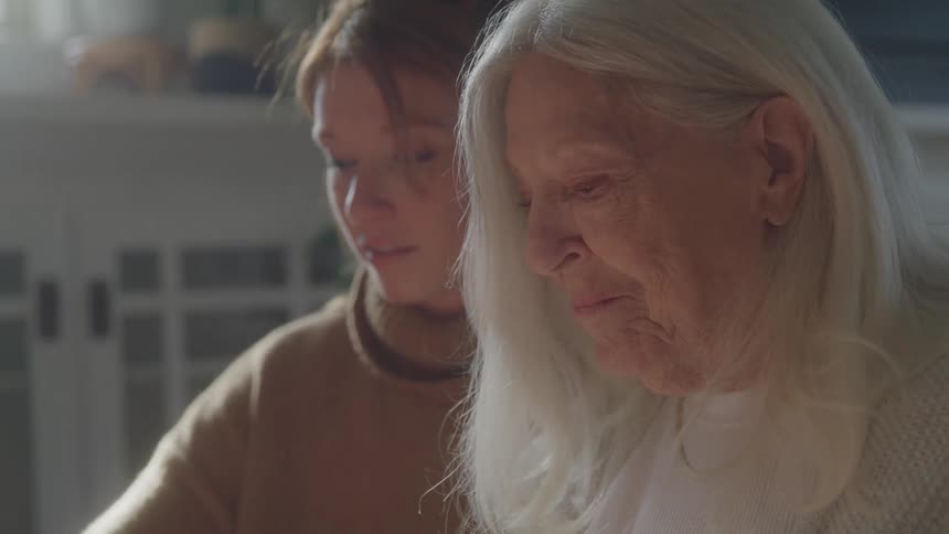 Young woman smiles beside an elderly woman with white hair