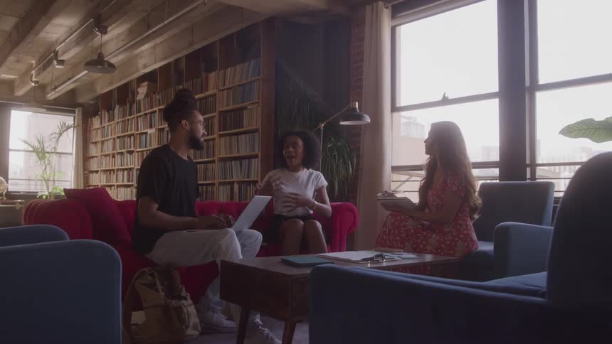 Three people work together in a room lit by large windows