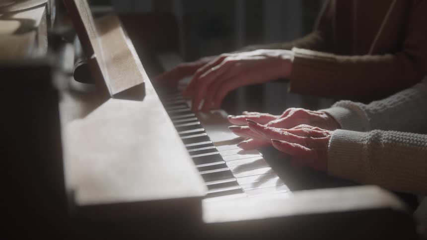 Two people play the piano together