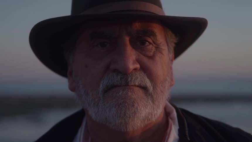 The man is standing on the shore at sunrise