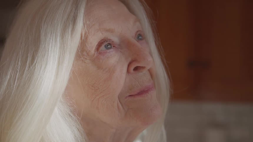 Elderly woman with white hair looking up with a serene expression