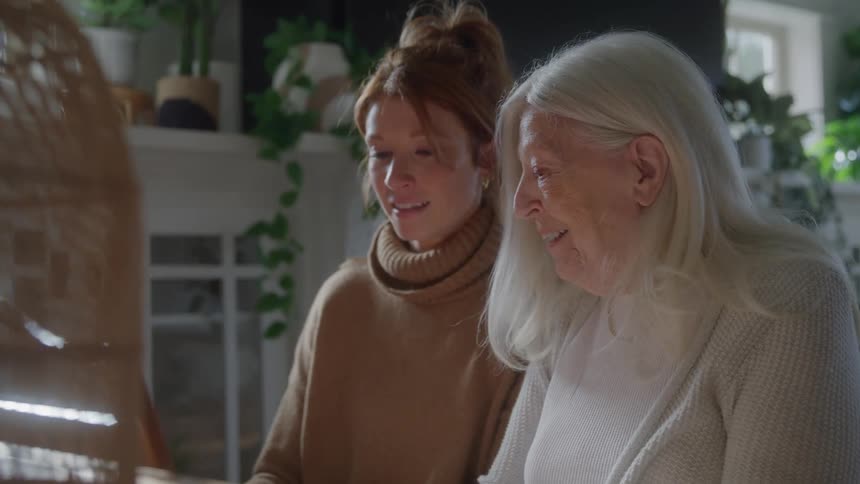 Two women look down and laugh together