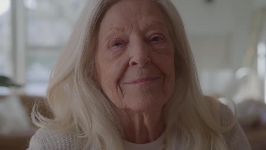 A woman smiles directly at the camera with her head and shoulders in the shot