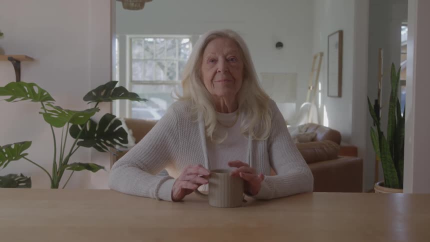 The woman sits at the table with a mug