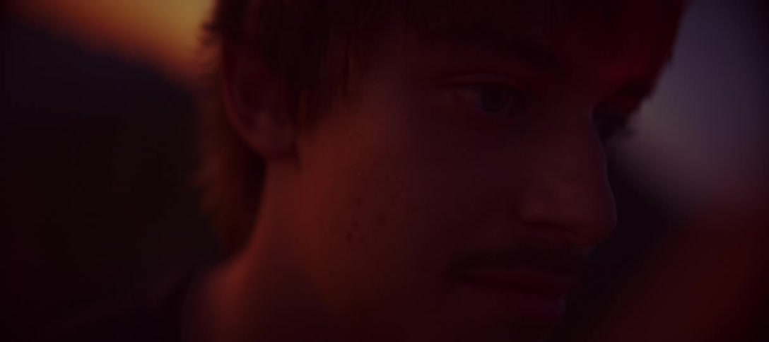 Face of a young man lit by reddish light at dusk