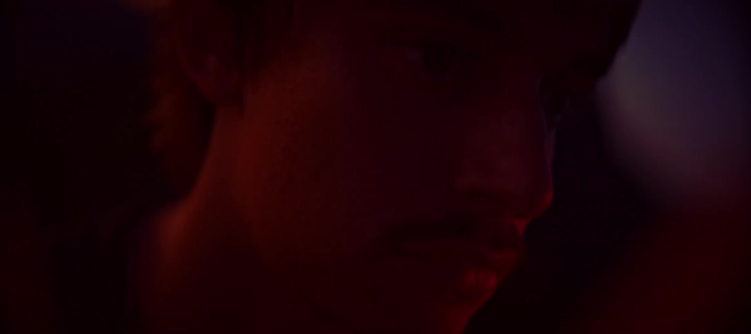 A mans face is lit by the flicker of a flame in the dark