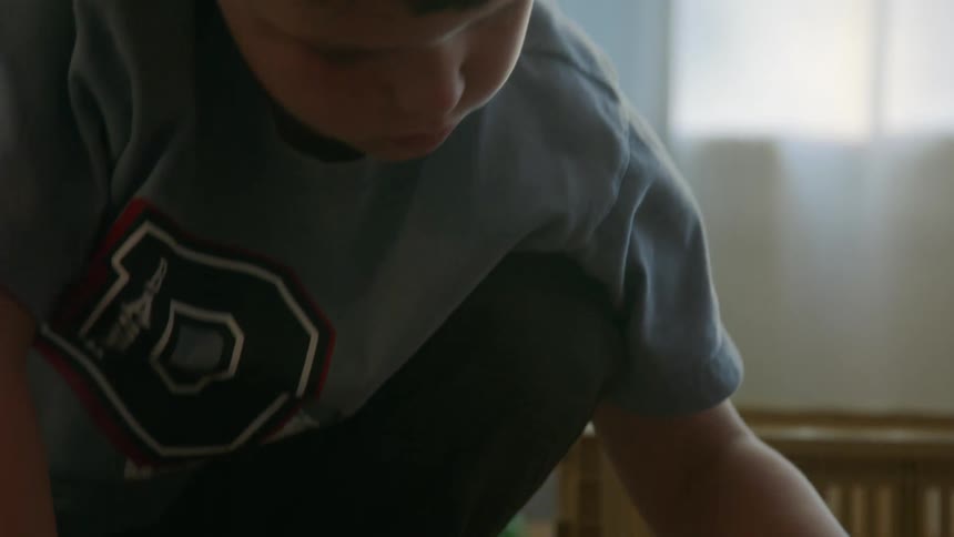 A child is on the floor and pushes a toy train on a track the train is pulled back and then pushed forward on the track