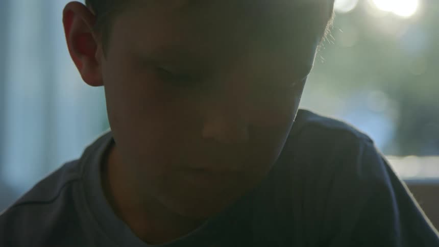 A boys face is shown as he looks to his right and then looks down