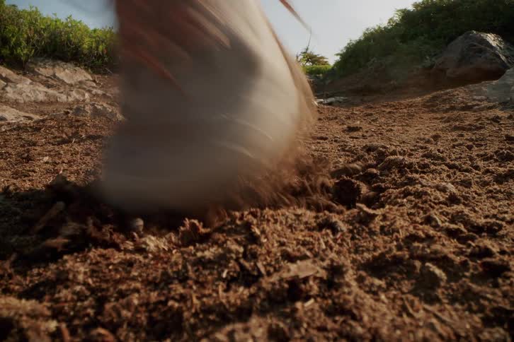 Person runs along a dirt trail surrounded by rocks and vegetation