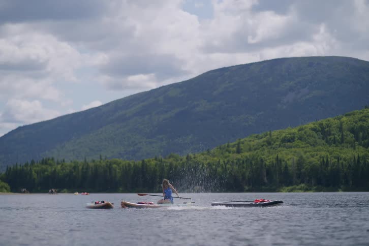 People enjoying stand up paddle boards on a lake surrounded by mountains