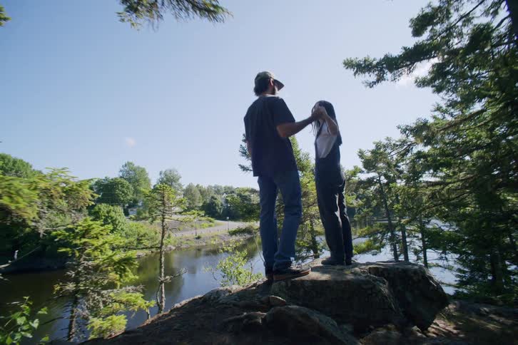 Couple dancing on top of a rock surrounded by trees and a lake