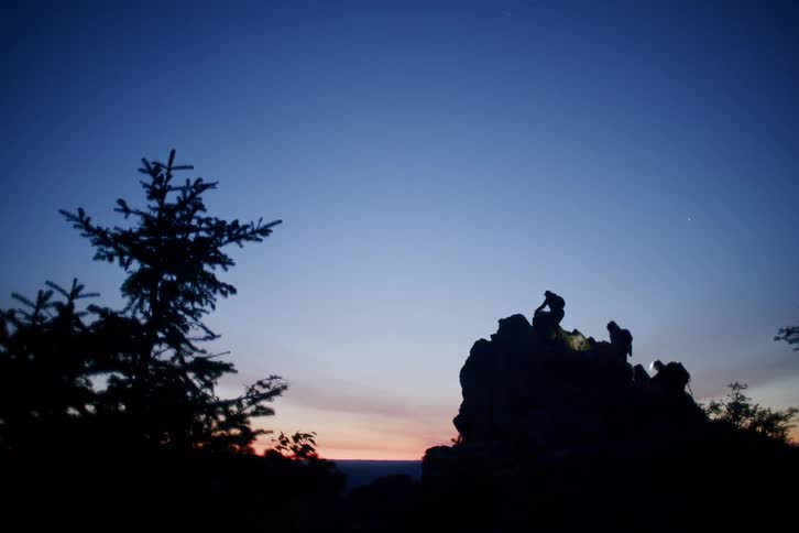 Silhouette of hikers hiking up a rock in the wildernes at sunrise