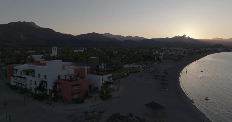 Coastal town at sunset with mountains in the background