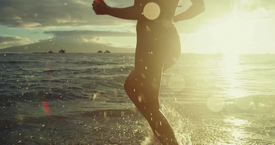 Silhouette of a woman running by the sea at sunset