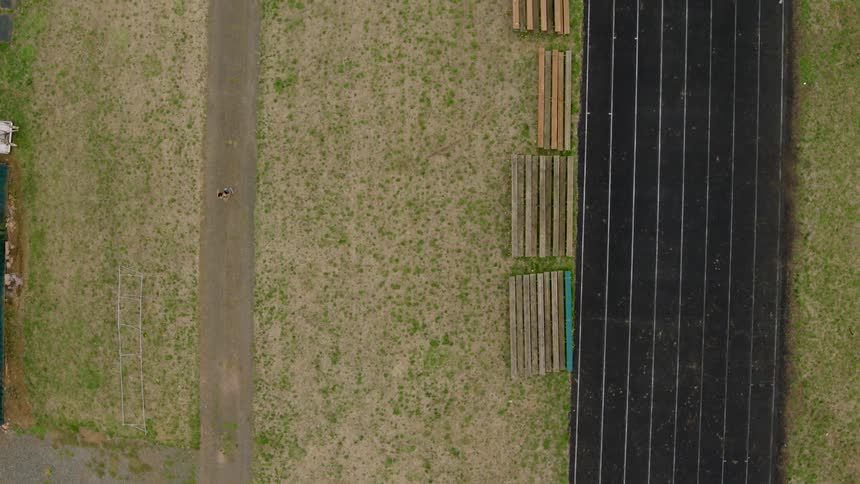A girl runs along a dirt path next to an old running track